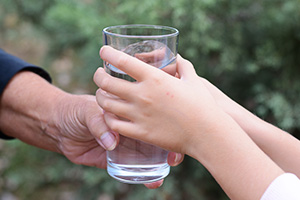 Person reicht einer anderen ein Wasserglas