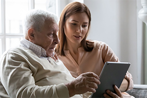 alter Mann und junge Frau schauen gemeinsam auf ein Tablet