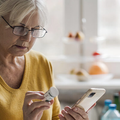 ältere Frau hält Kopfschmerzen Medikamente in der Hand