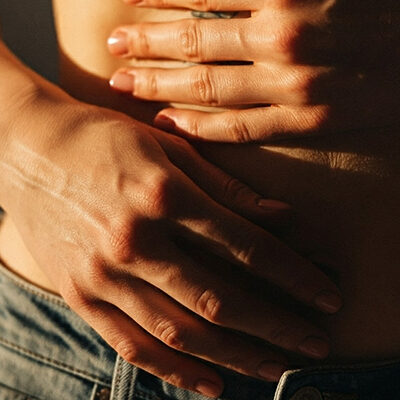 Frau hält sich den Bauch bei Morbus Crohn